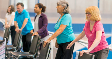 Elderly patients exercising behind chairs