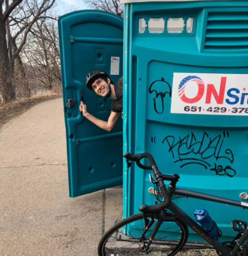 Jonathan Papko leaning out of a portable toilet