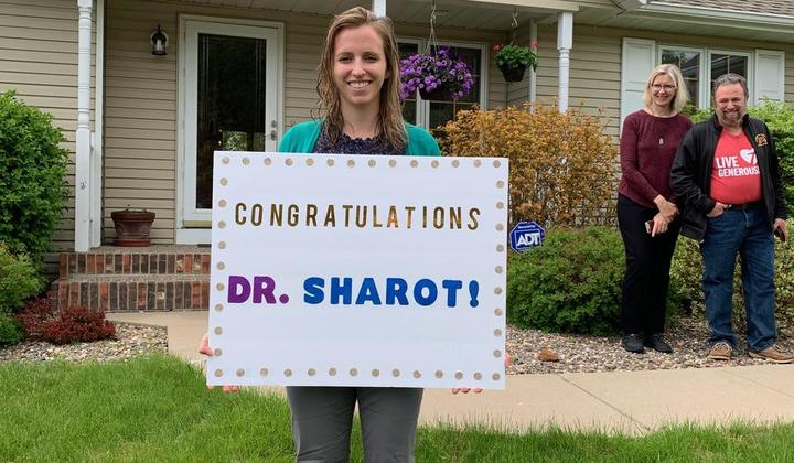DNP graduate holding a sign saying Congratulations Dr. Sharot!