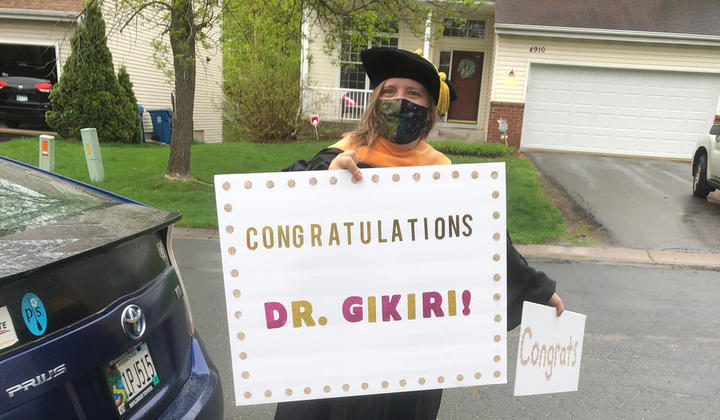 DNP graduate Dr. Gikiri holding her congratulations sign from her professors