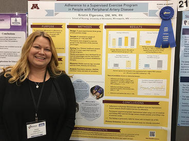 Kristin Elgersma standing in front of her research day poster with a blue ribbon on it
